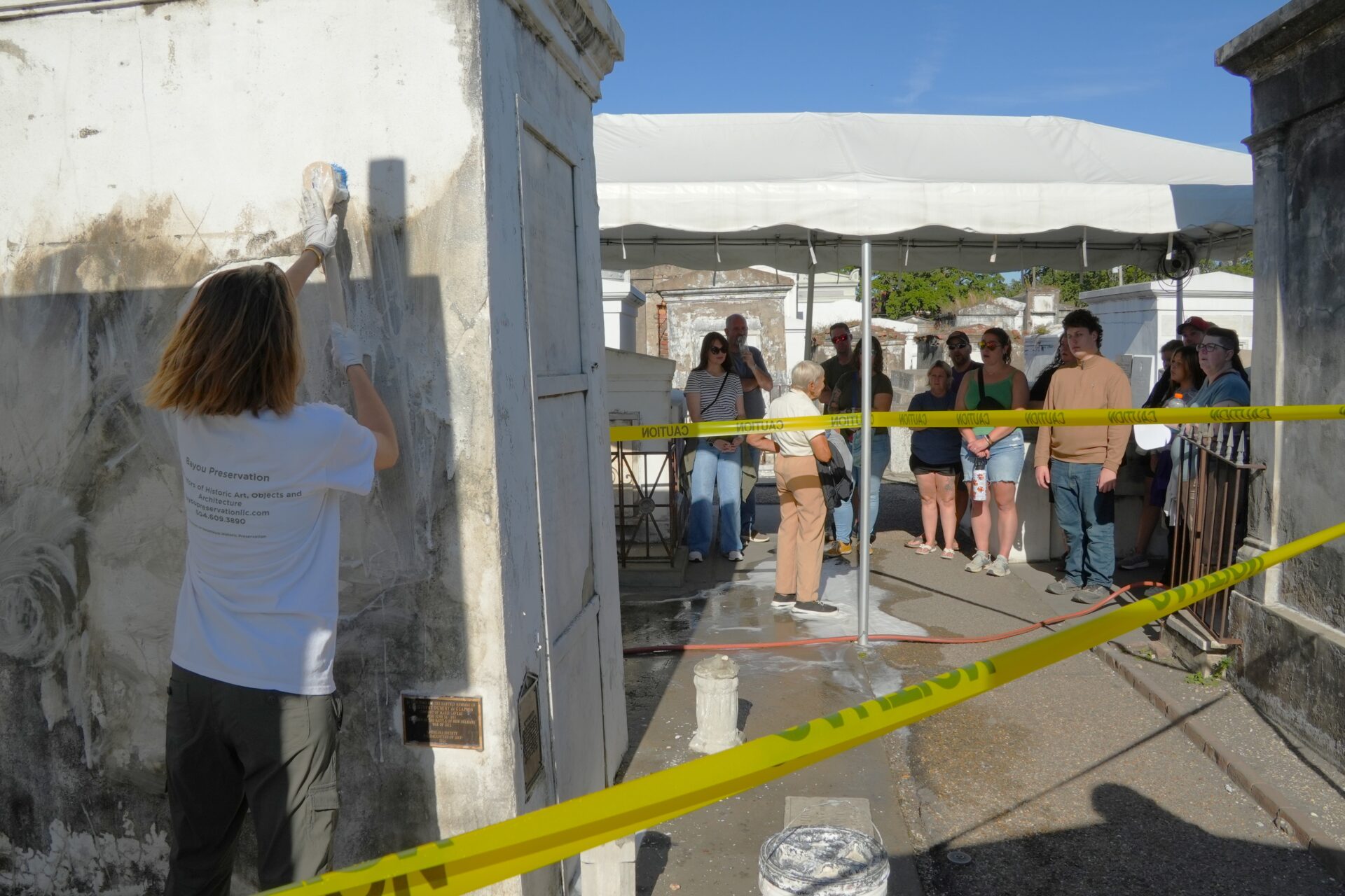Visitors to St. Louis Cemetery No. 1 watch Juliette Hotard of Bayou Preservation clean the tomb of Marie Laveau.