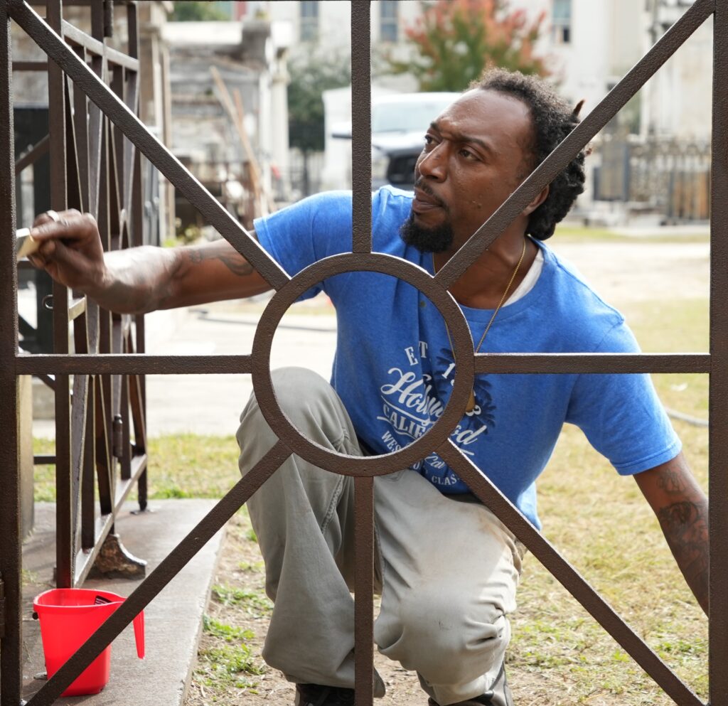 Kendrick Wilkerson makes repairs to an iron fence around a tomb.