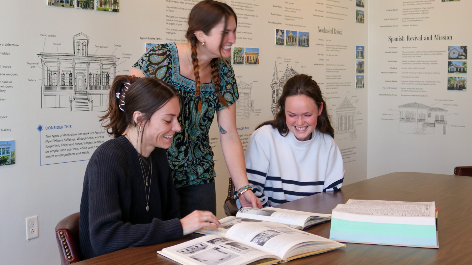 3 PRC Interns gather around a conference table to review their research.
