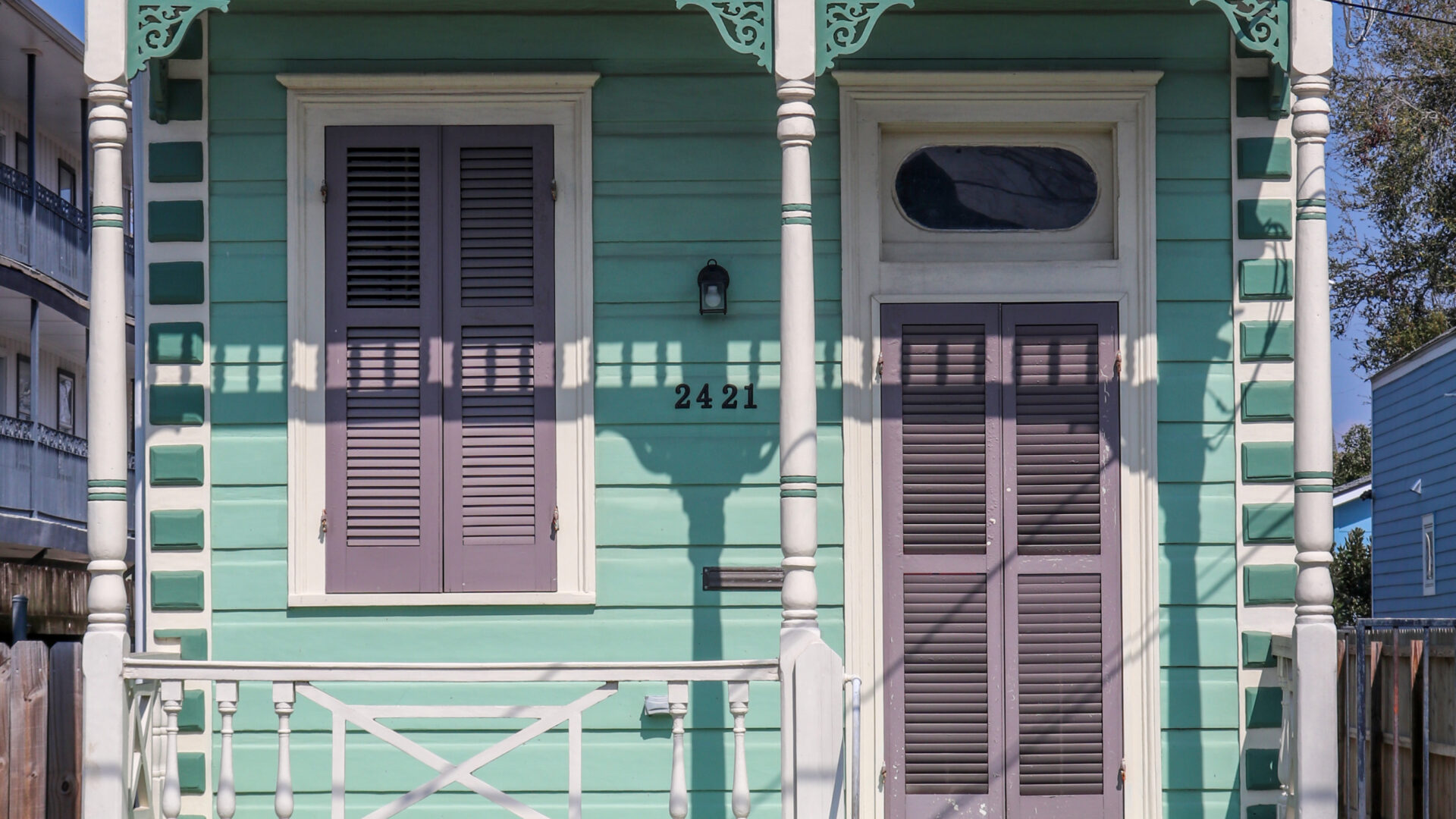 Front Facade of a 2-bay teal and purple eastlake style shotgun home.