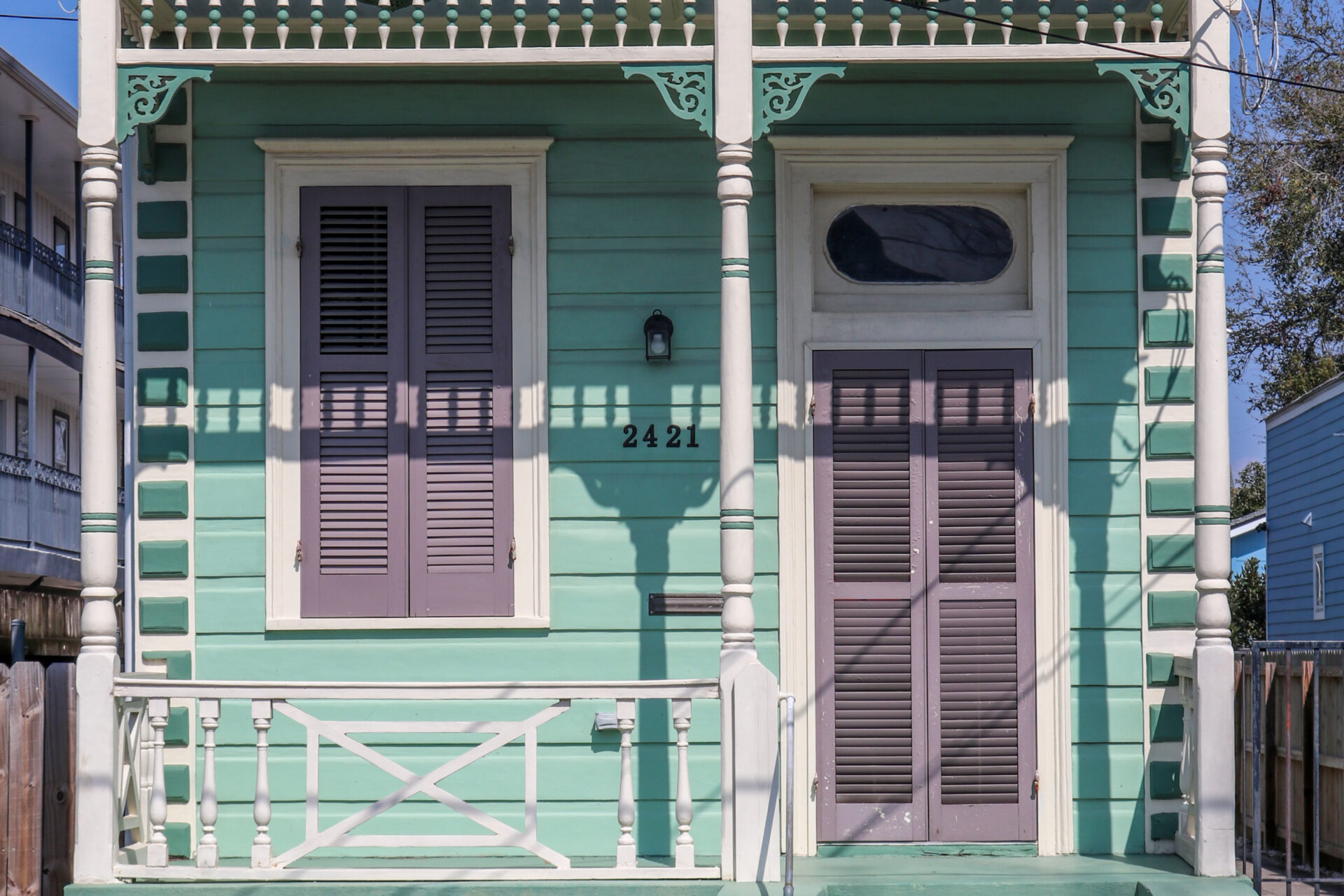 Front Facade of a 2-bay teal and purple eastlake style shotgun home.