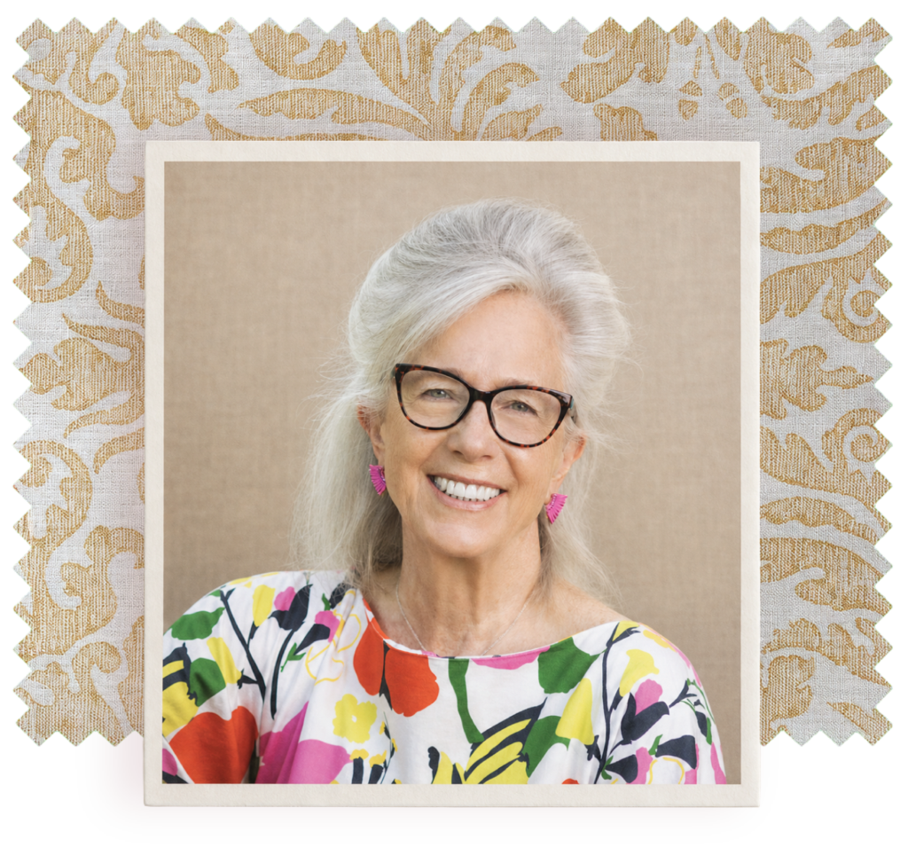 Portrait of Margot Shaw, smiling and wearing glasses and a colorful floral blouse, framed by a decorative cream-and-gold patterned border.