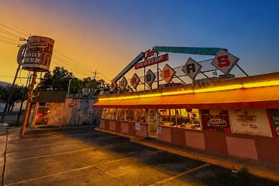 Ted’s Frostop restaurant at dusk, with vintage neon signage, a rooftop sign and illuminated storefront.
