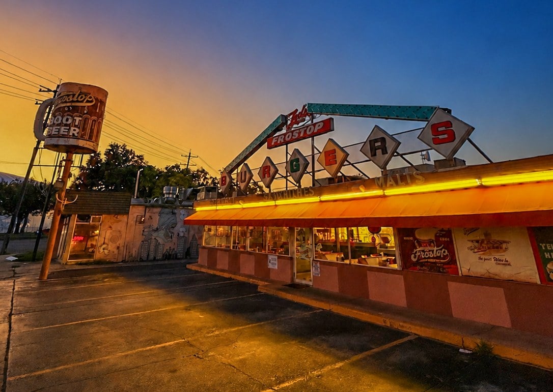 Ted’s Frostop restaurant at dusk, with vintage neon signage, a rooftop sign and illuminated storefront.