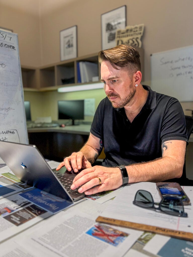 Clint Durrett, PRC director of communications, works on a laptop at a desk in the PRC office.