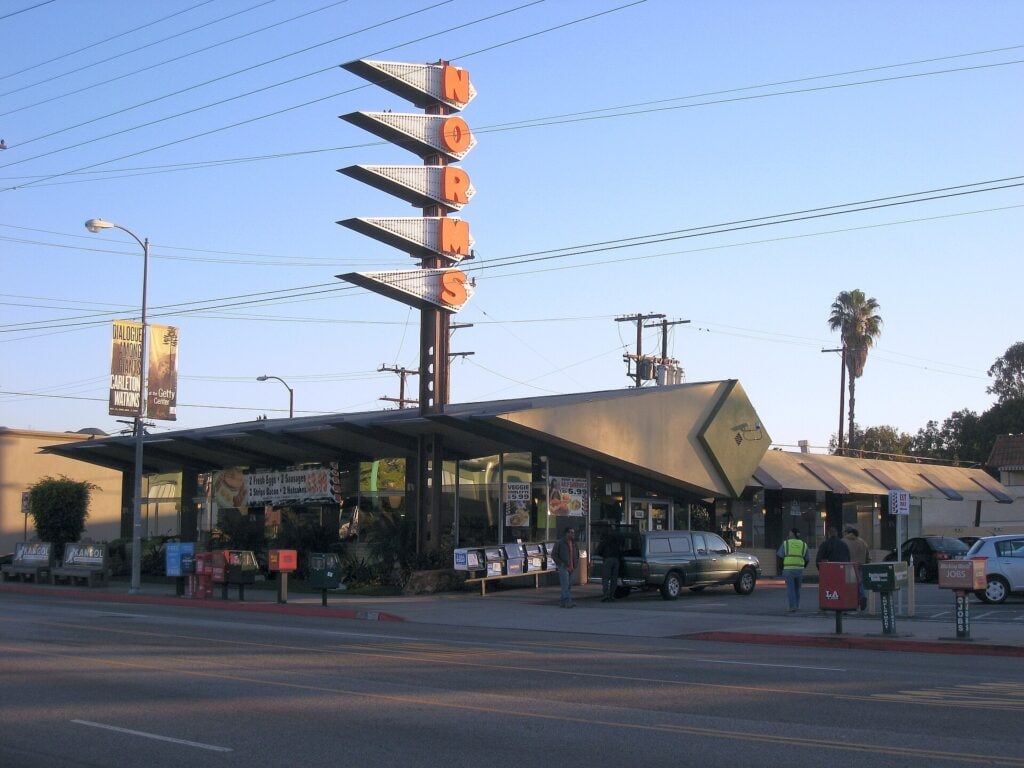 Norms restaurant on Los Angeles, CA with a distinctive mid-century modern building, angular roofline and tall vertical “NORMS” sign.