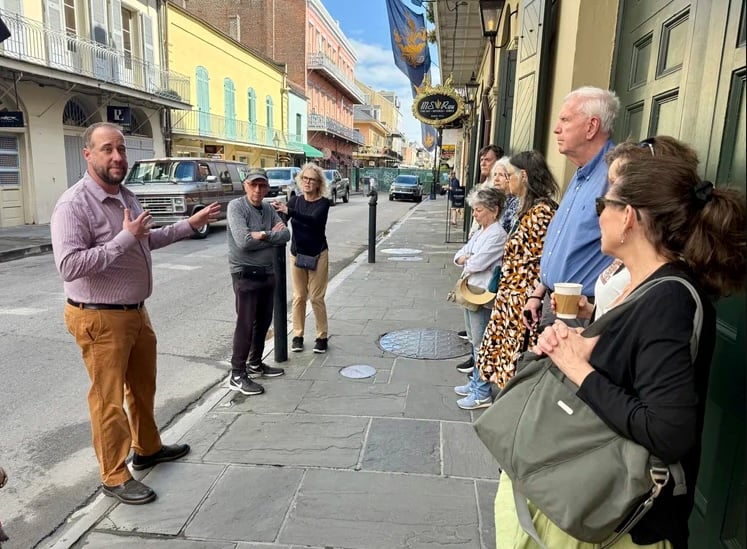 Russell Blanchard leads a walking tour through the French Quarter, speaking to a group gathered along a historic New Orleans street.