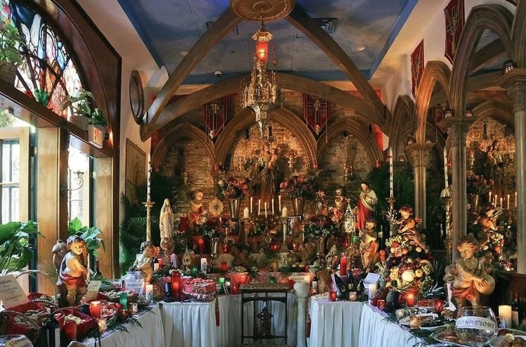 St. Joseph’s altar at Irene’s in New Orleans, richly decorated with religious statues, flowers, candles, food, and other offerings beneath a Gothic-style interior.