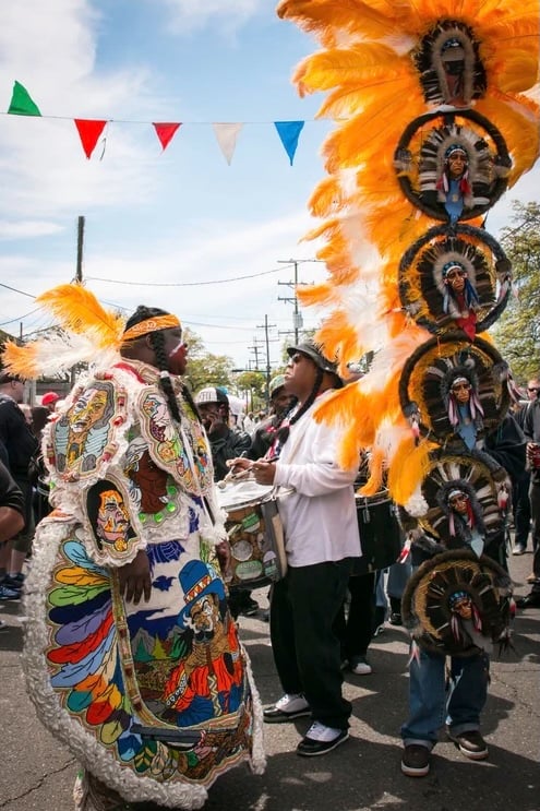 Super Sunday celebration in New Orleans, featuring participants in elaborate feathered Mardi Gras Indian suits and headdresses during a street procession.