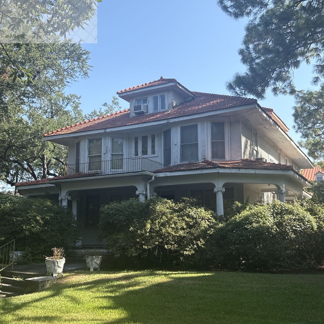 8133 Spruce Street, a historic two-story residence with a red tile roof, white siding, covered front porch, and second-story balcony, surrounded by mature trees and a landscaped lawn.