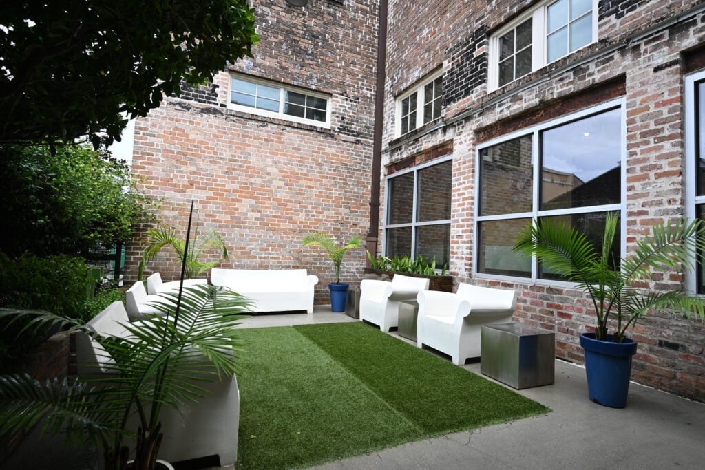Brick courtyard at St. Joe Lofts with white outdoor seating and potted palms
