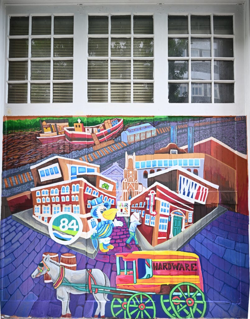 Colorful mural depicting New Orleans buildings, boats, a streetcar and horse-drawn wagon